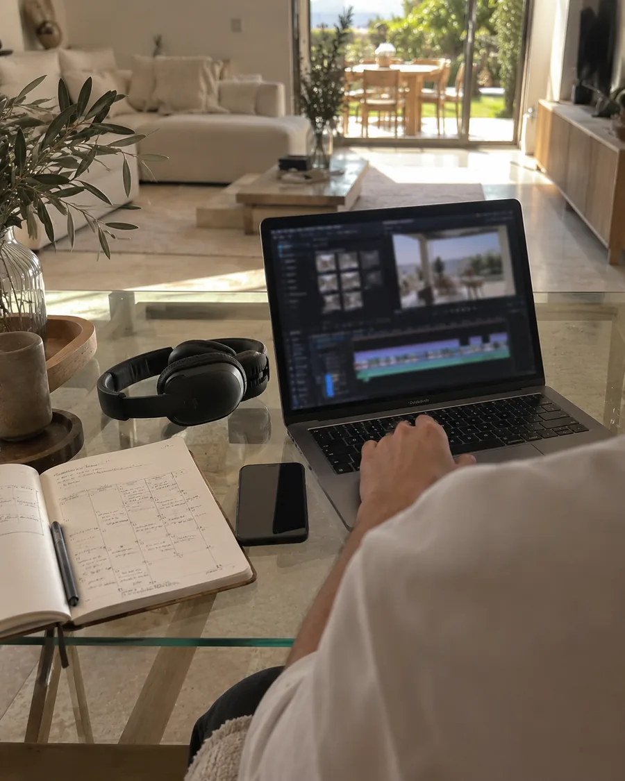 Portátil con una línea de tiempo de edición de vídeo, auriculares y un calendario de contenidos a mano